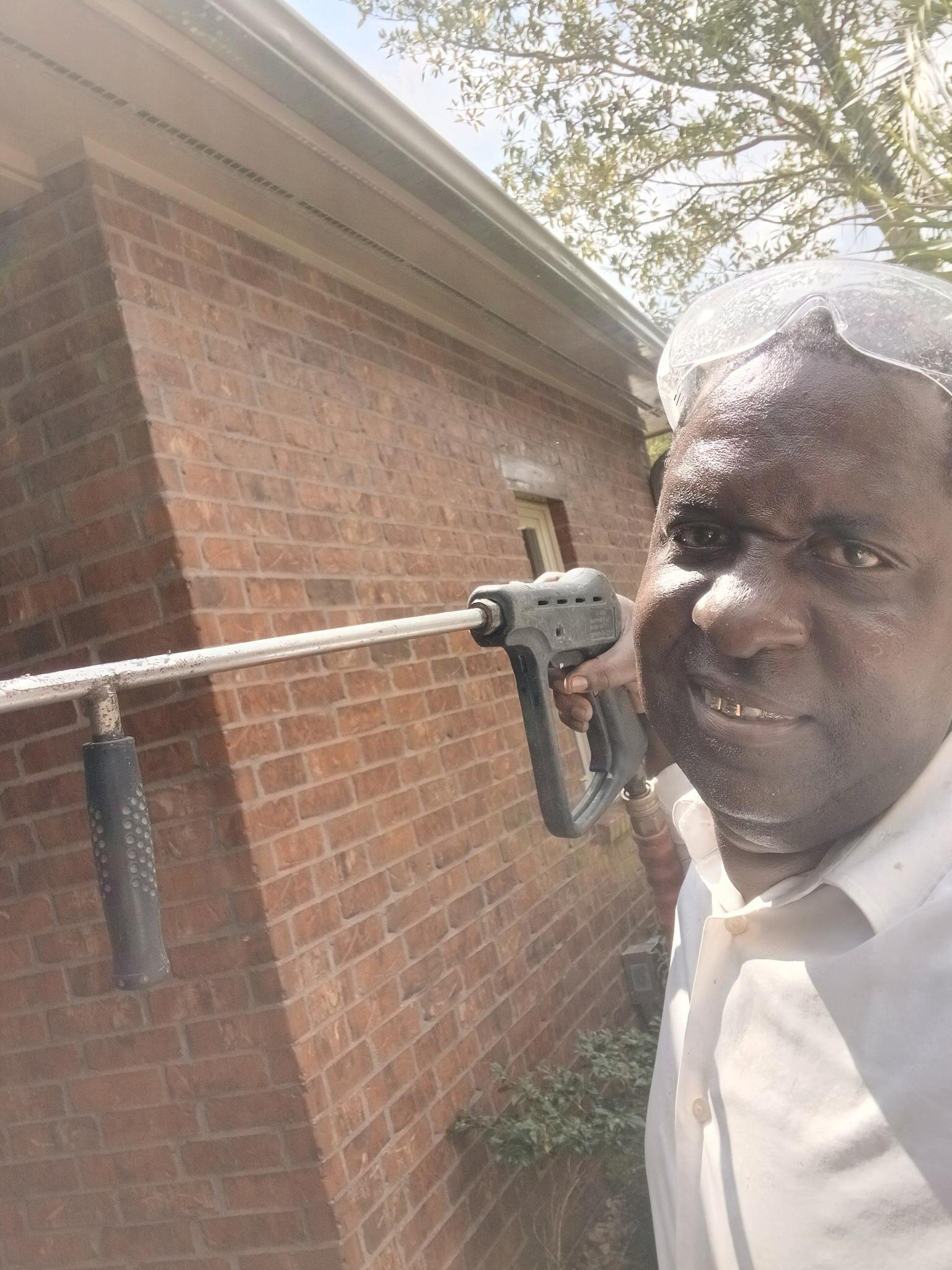 Alton Vallian on a residential house wash — wand in hand, brick siding